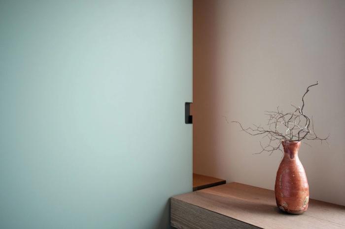 Detail of a frosted pocket door panel and handle hardware beside a wood shelf